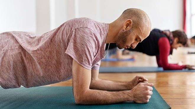 Man håller en statisk underarmsplanka på en träningsmatta